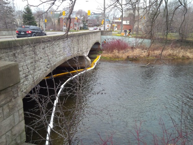Booms placed along Neeve Street bridge to contain and absorb vegetable oil from storm drain spill.