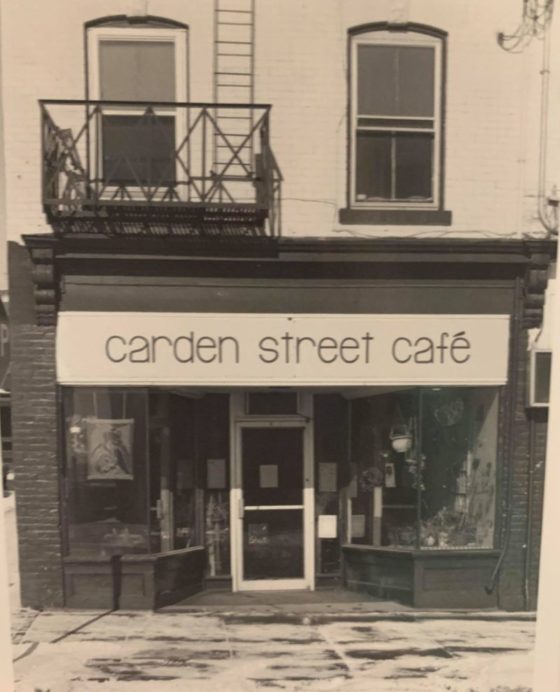 A sepia-toned photograph of ‘carden street café,’ a glass-windowed, shopfront on a sidewalk with a fire escape above it.