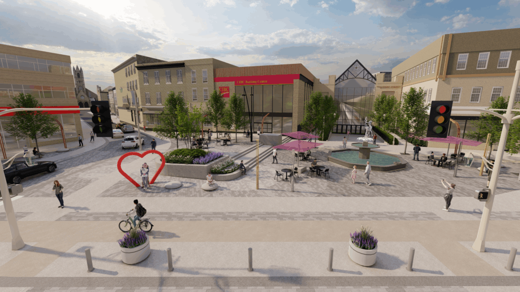 Daytime view of an urban plaza with a central fountain featuring a statue. Purple shade umbrellas cover seating areas, and landscaped planters with greenery line the space. People are walking and sitting at tables. Surrounding buildings include a glass atrium and a bank with a red sign reading “CIBC Banking Centre.” The sky is partly cloudy with sunlight streaming through.