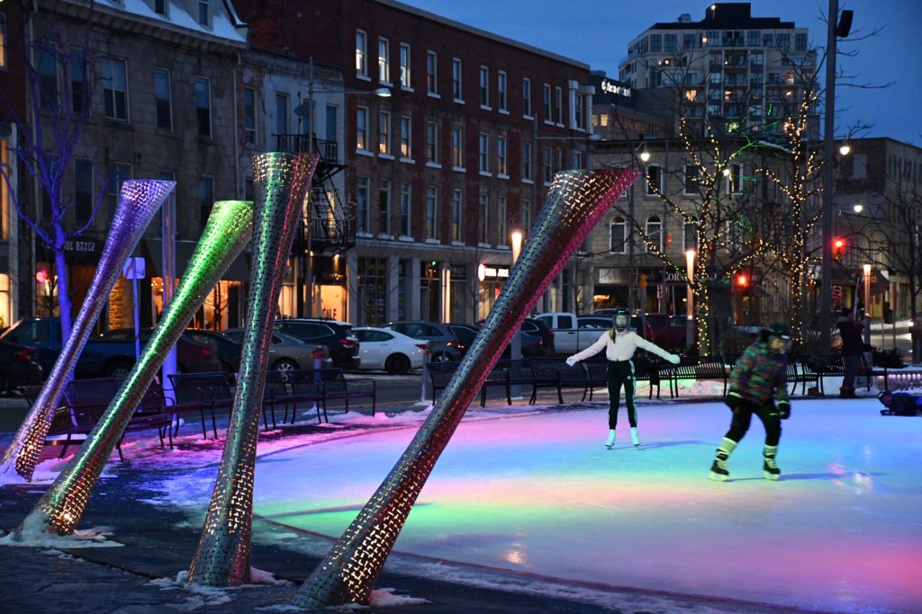 Skaters skate at Market Square ice rink lit with blue and pink lights.