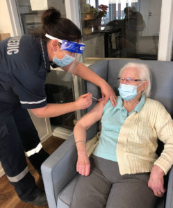 Paramedic administering Pfizer COVID-19 vaccination to a long-term care resident.