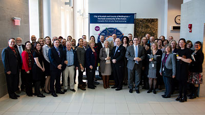 Attendees of the Smart Cities Challenge reception standing in a horseshoe formation. The photo was taken in the galleria inside Guelph City Hall.