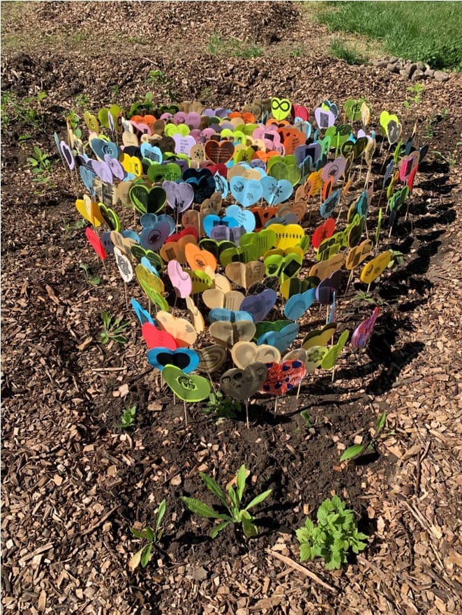 a cluster of small paper hearts attached to sticks are shown planted in the ground