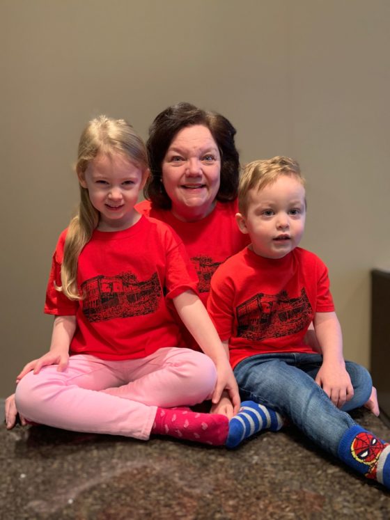 A photo of the participant wearing the silkscreened t-shirt with two toddler-aged children in matching t-shirts.