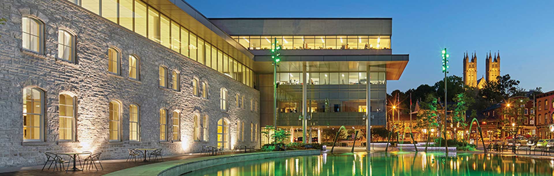The front of City Hall in the evening with the splash pad and fountains