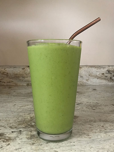 green smoothie in glass with a straw