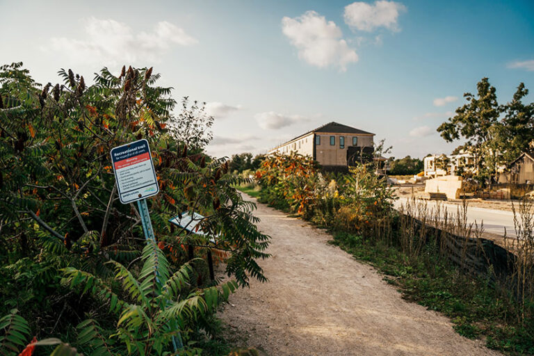 dirt  road with trees on one side and small building on the other