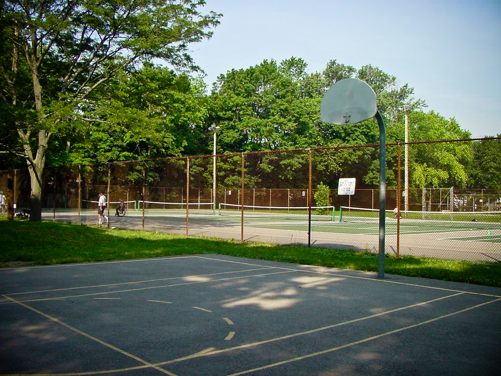 Half basketball court in front of fenced in tennis courts
