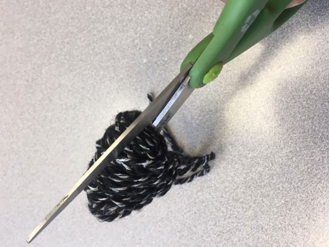 cutting yarn to form pom pom