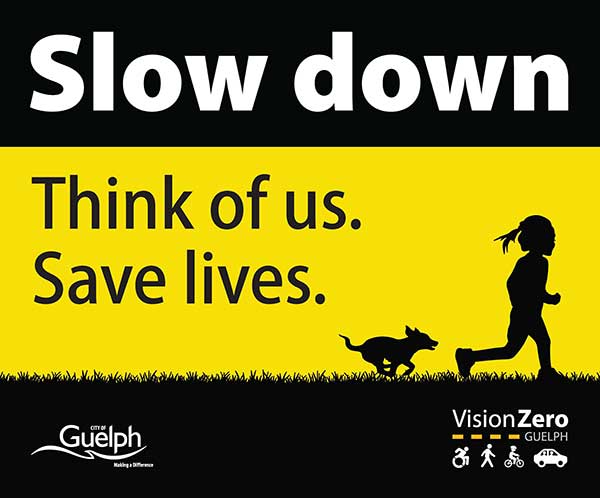 Sign with silhouette of a child and a dog running and text that says "Slow down. This of us. Save lives."