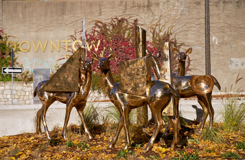 4 statues of deer in front of Downtown Guelph sign